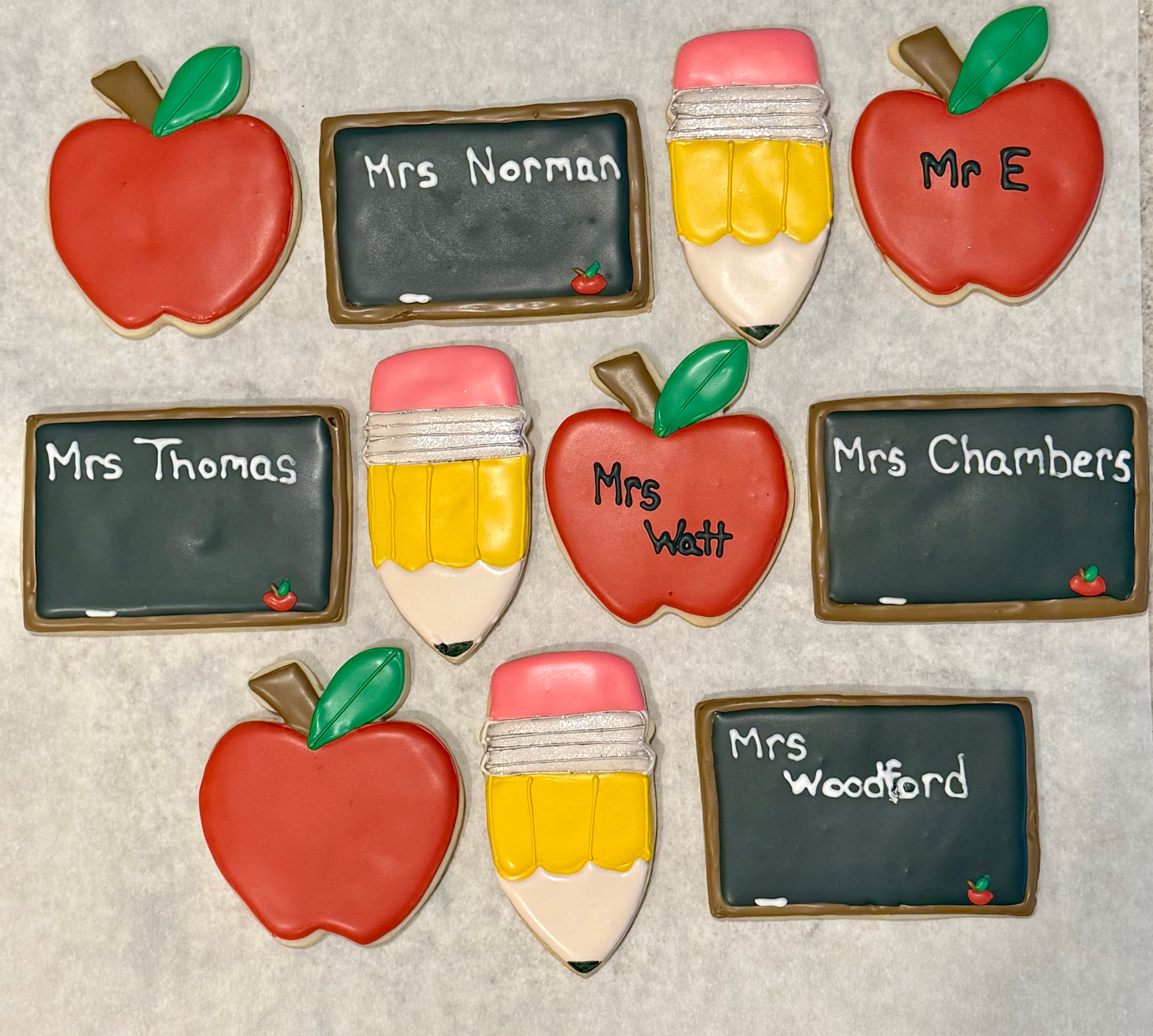 Custom school-themed sugar cookies with apples, chalkboards, and teachers' names